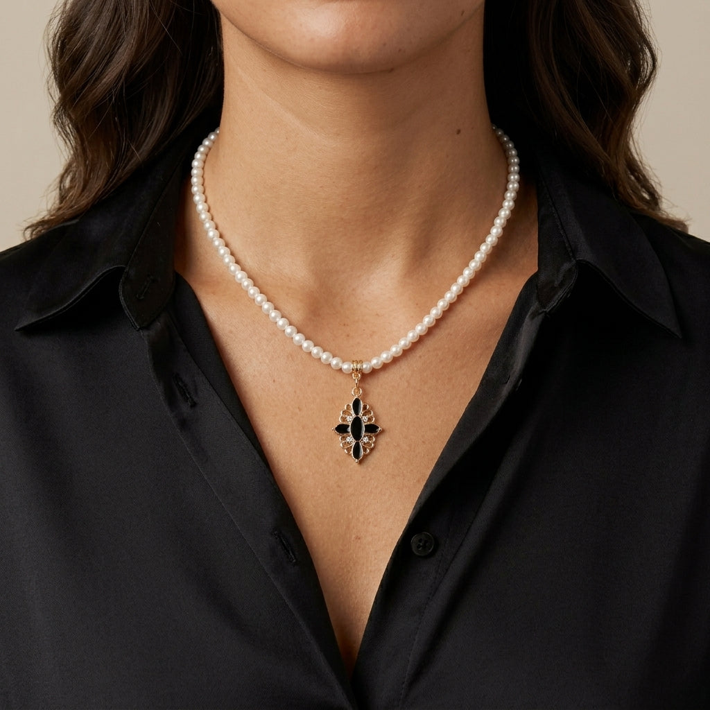 Woman in a black outfit wearing a white faux pearl necklace with a black stone cross and crystal pendant