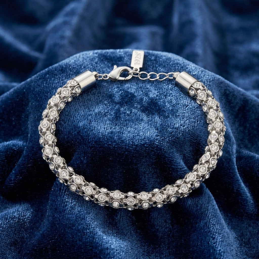 Silver bracelet with clear crystals on a blue textured fabric background