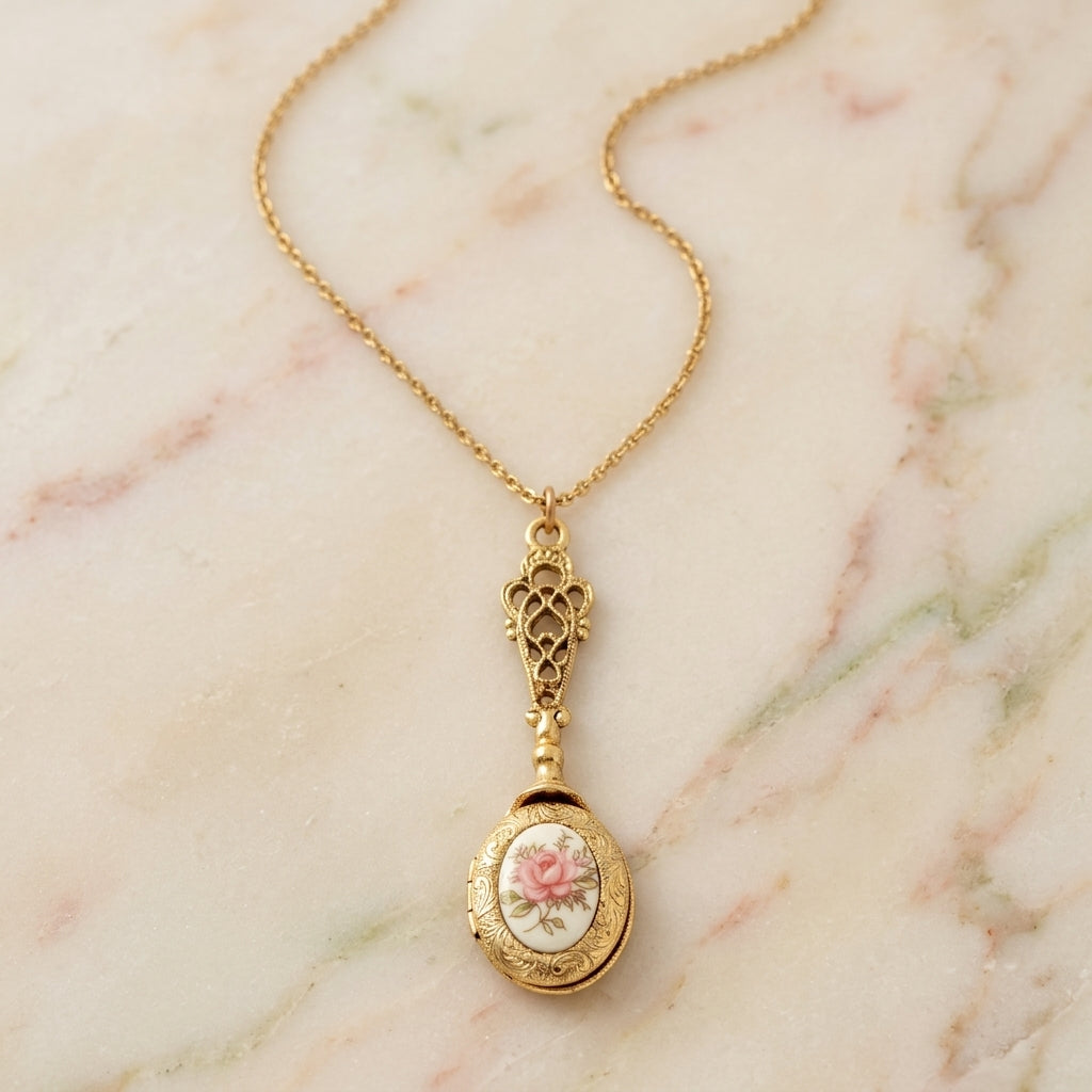 Gold locket necklace with a decorative floral pendant on a marble surface