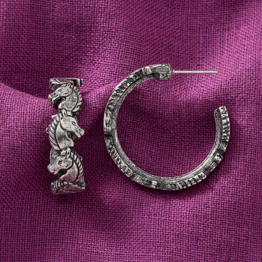 Antiqued Pewter Horse Hoop Earrings resting on light purple linen