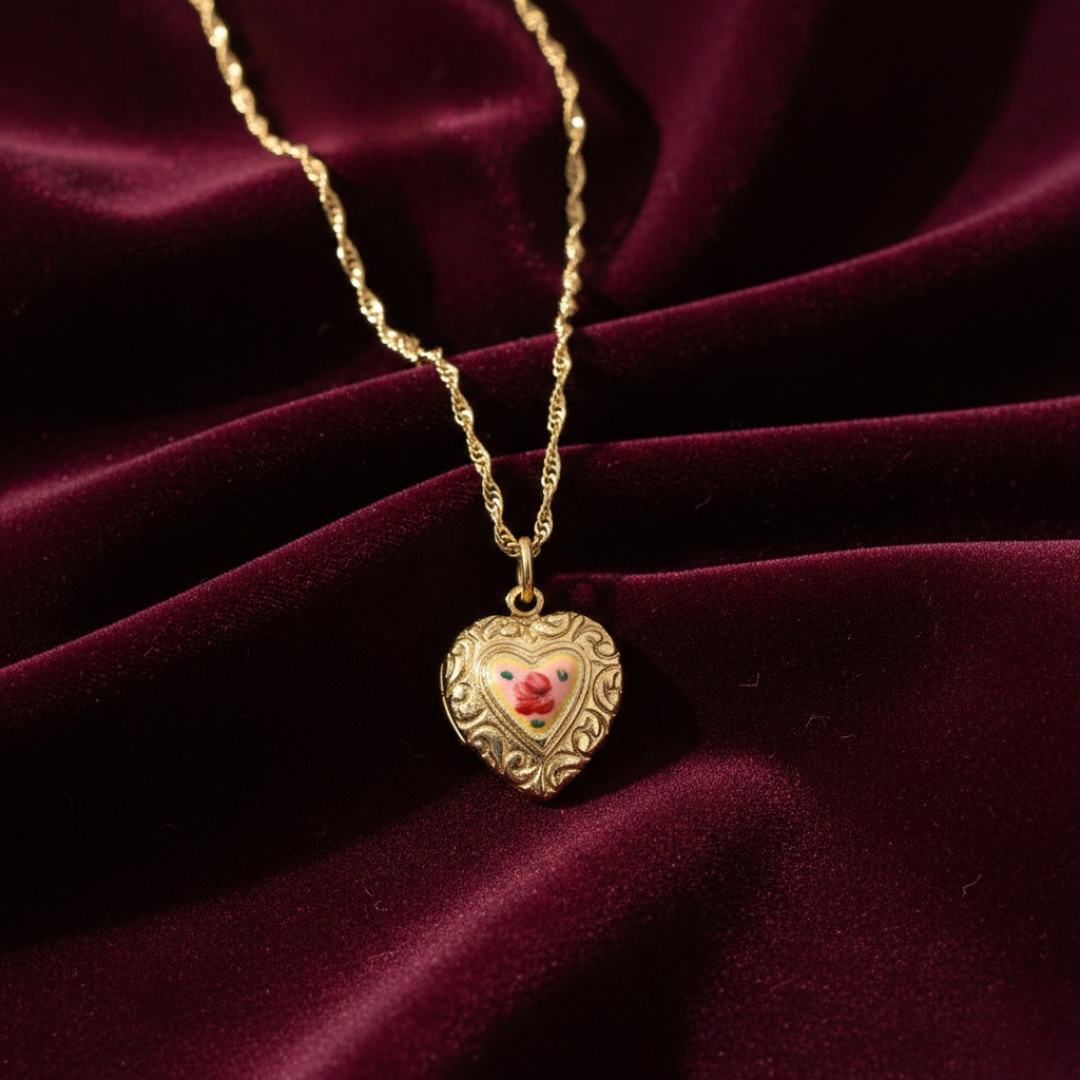 Gold heart-shaped locket with a floral pendant on a burgundy velvet background