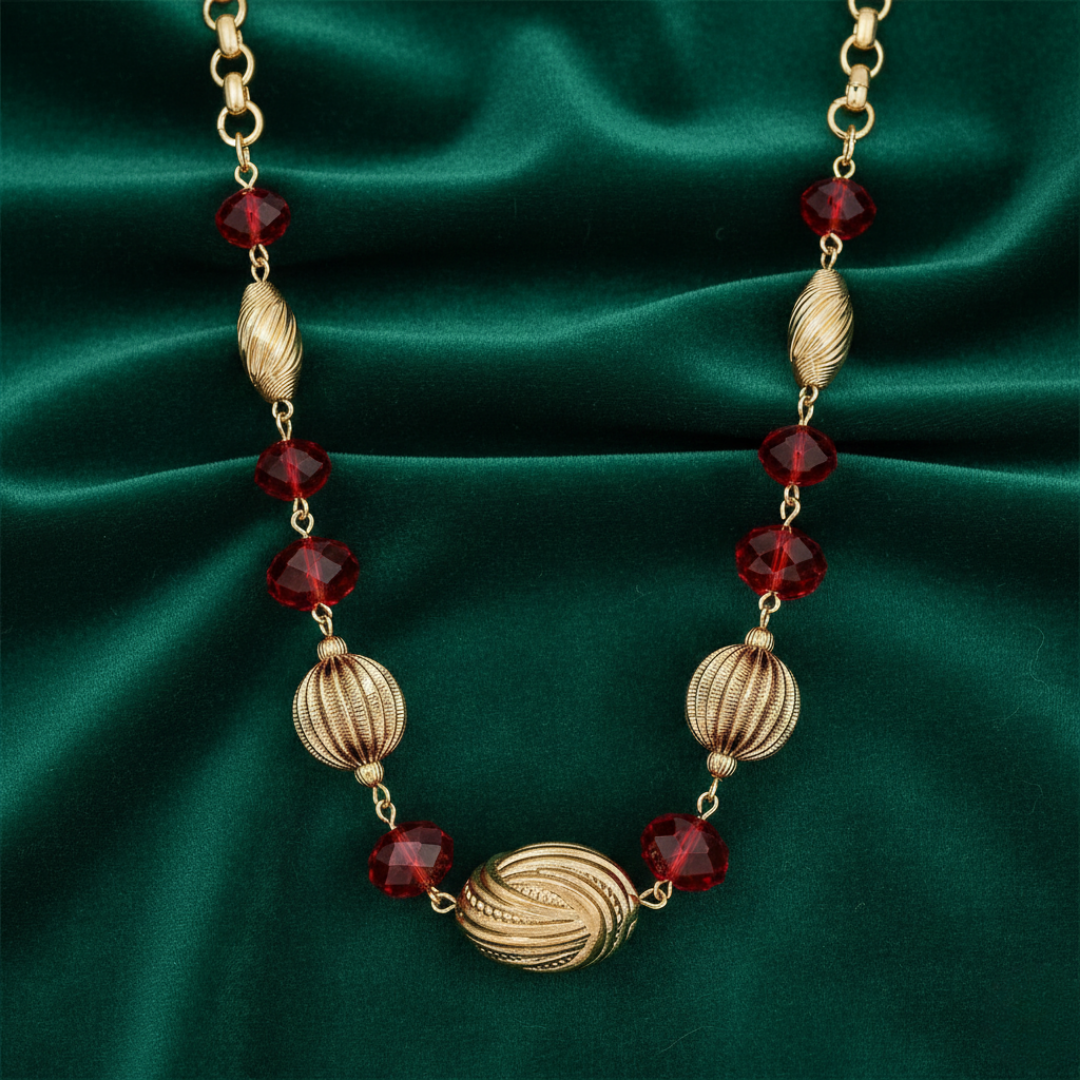 Gold necklace with red beads on a green satin background
