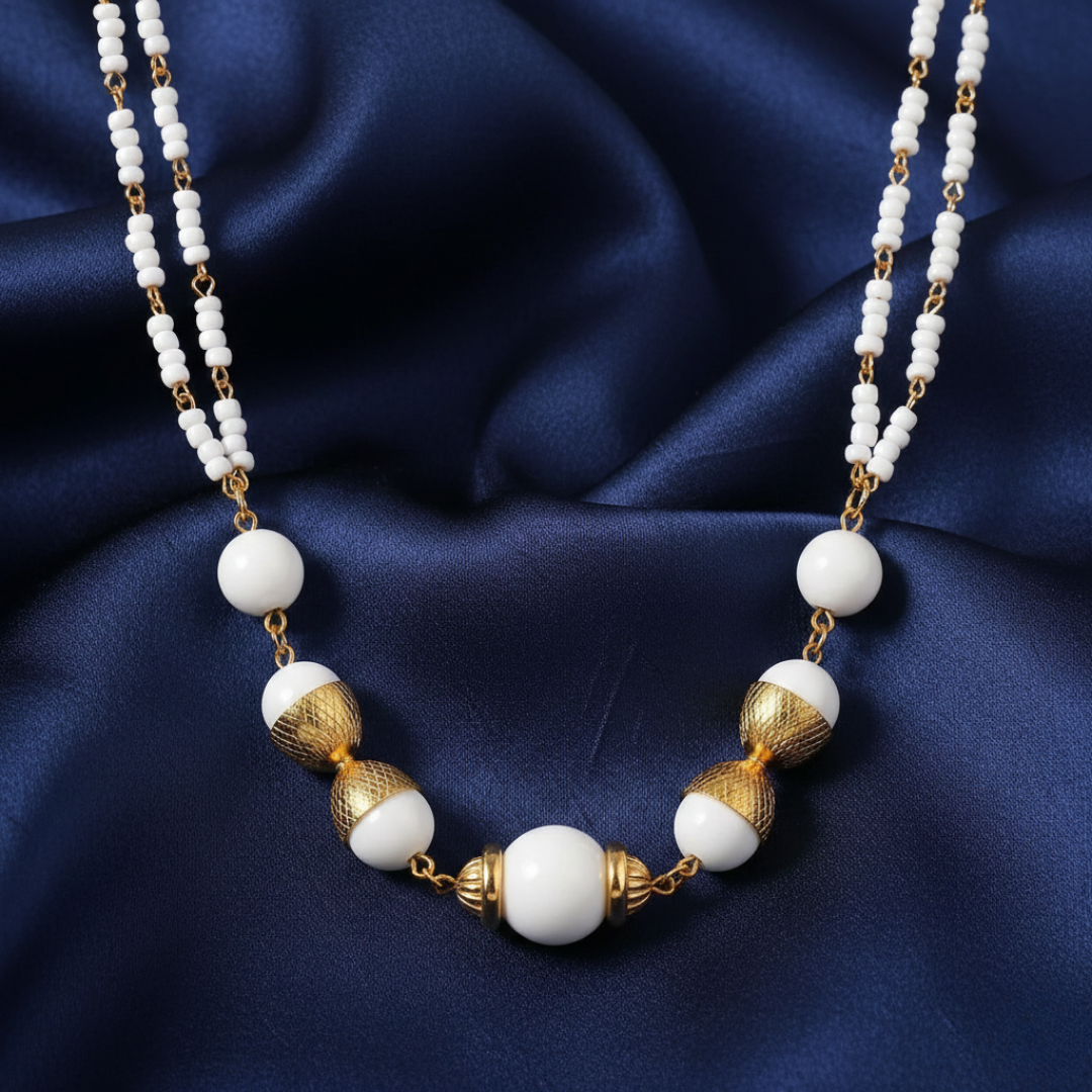 Necklace with white beads and gold accents on a blue fabric background