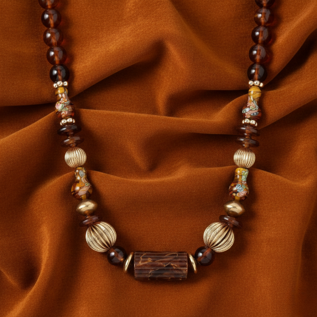 Necklace with brown and gold beads on a rust-colored fabric background