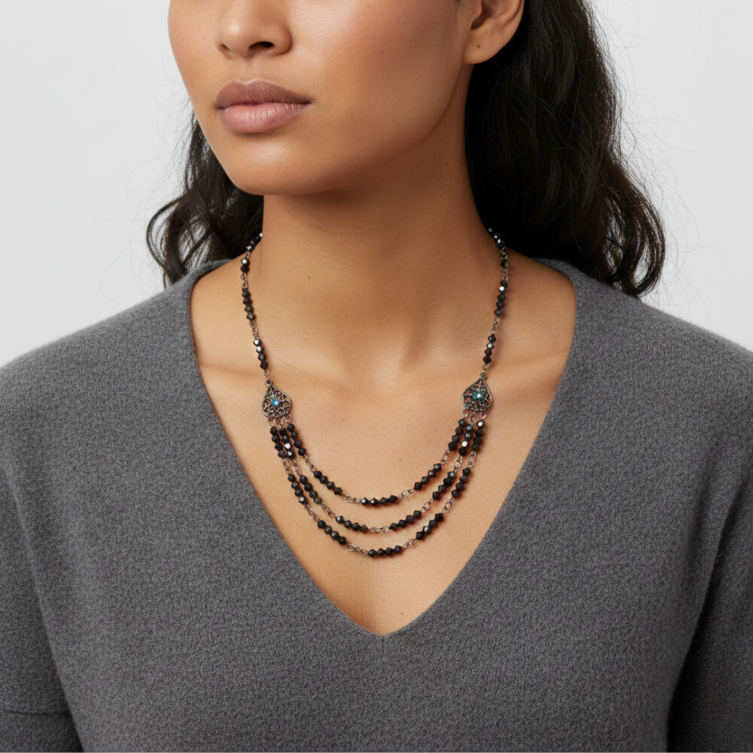 Woman wearing a layered bib necklace with a gray top against a white background