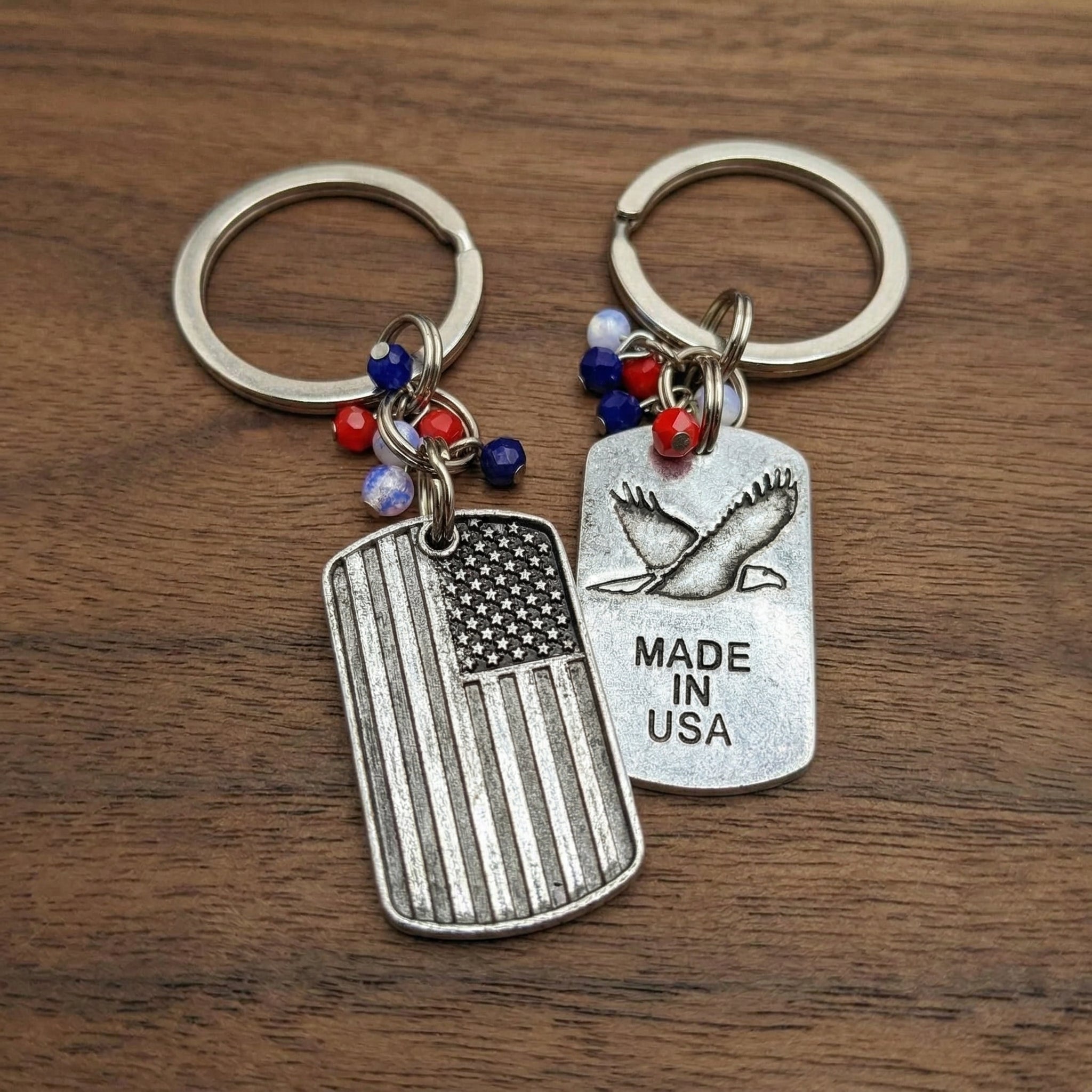 Two keychains with American flag and eagle design on a wooden surface