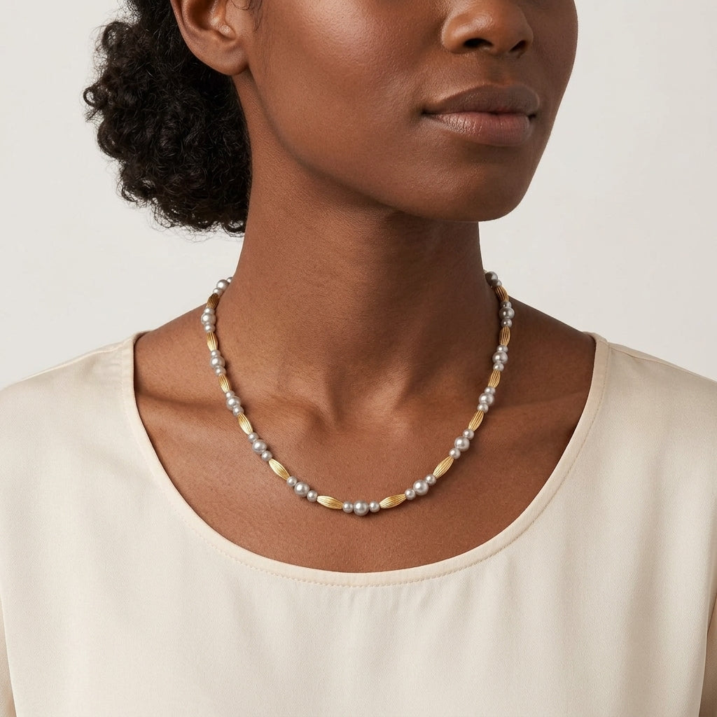 Woman wearing a pearl necklace with skinny beads against a neutral background