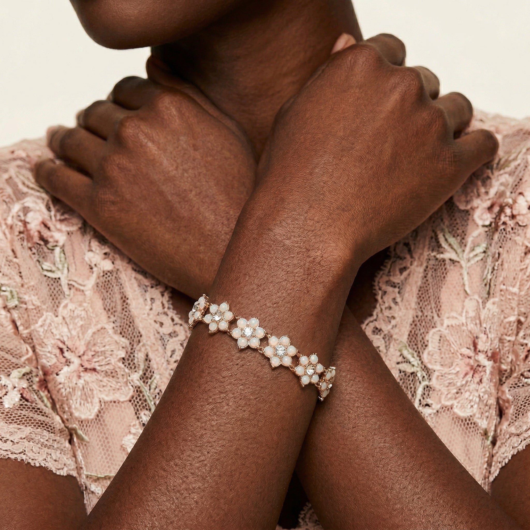 Close-up of a person wearing a delicate bracelet with opal radiance floral design on a lace fabric background