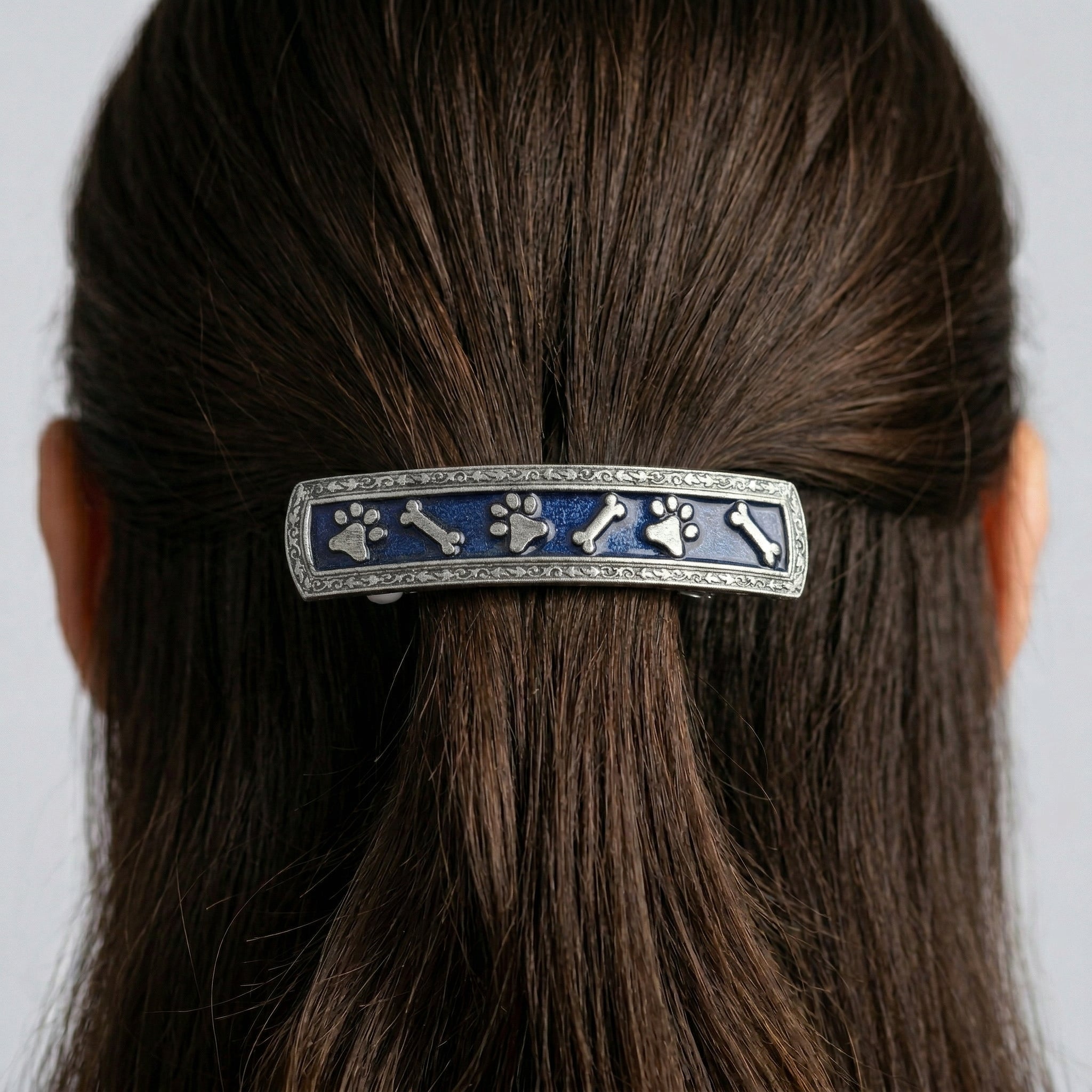 Hair barrette with pet paws and bones design in a person's hair against a neutral background