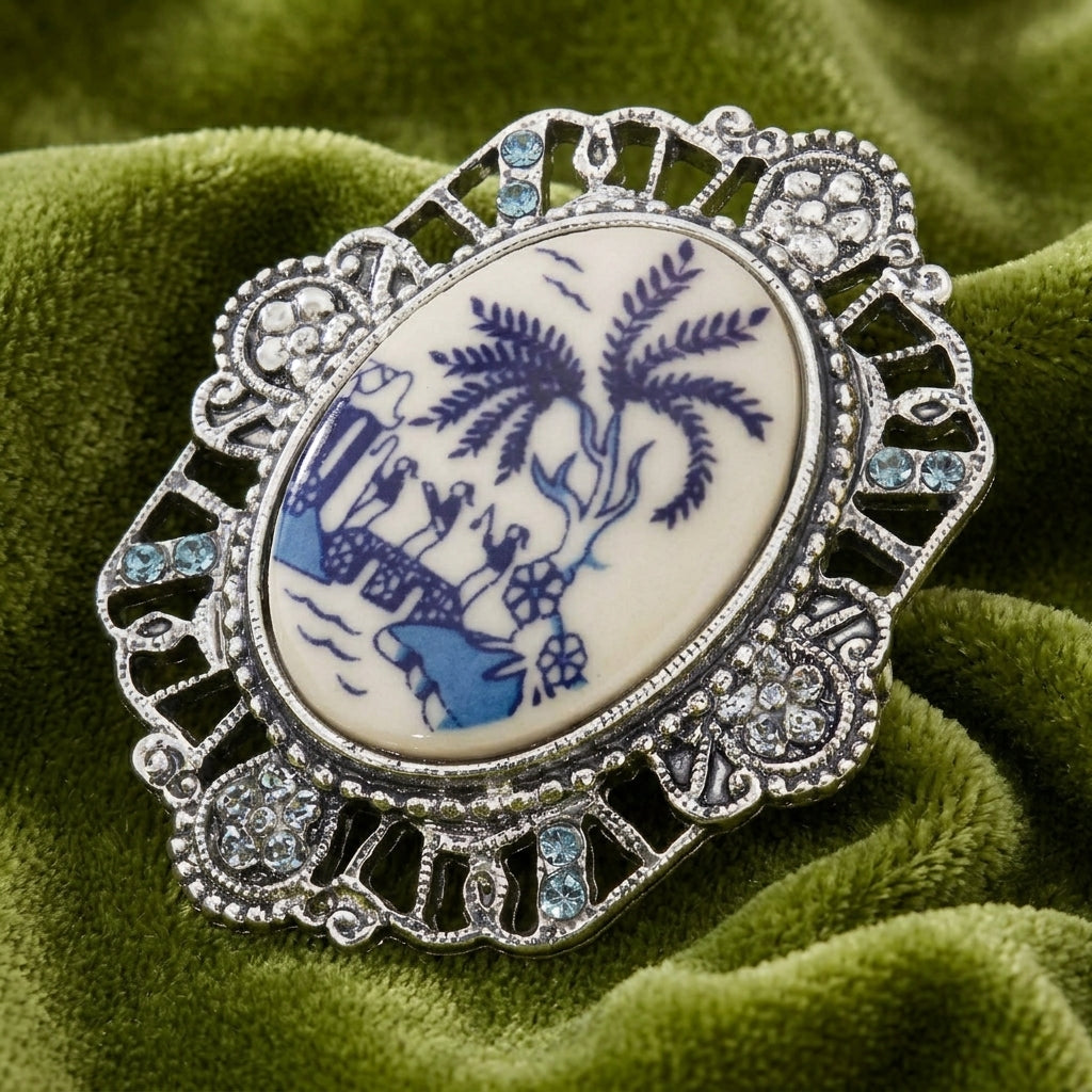 Decorative brooch with blue and white design and light blue sapphire crystals on a green fabric background