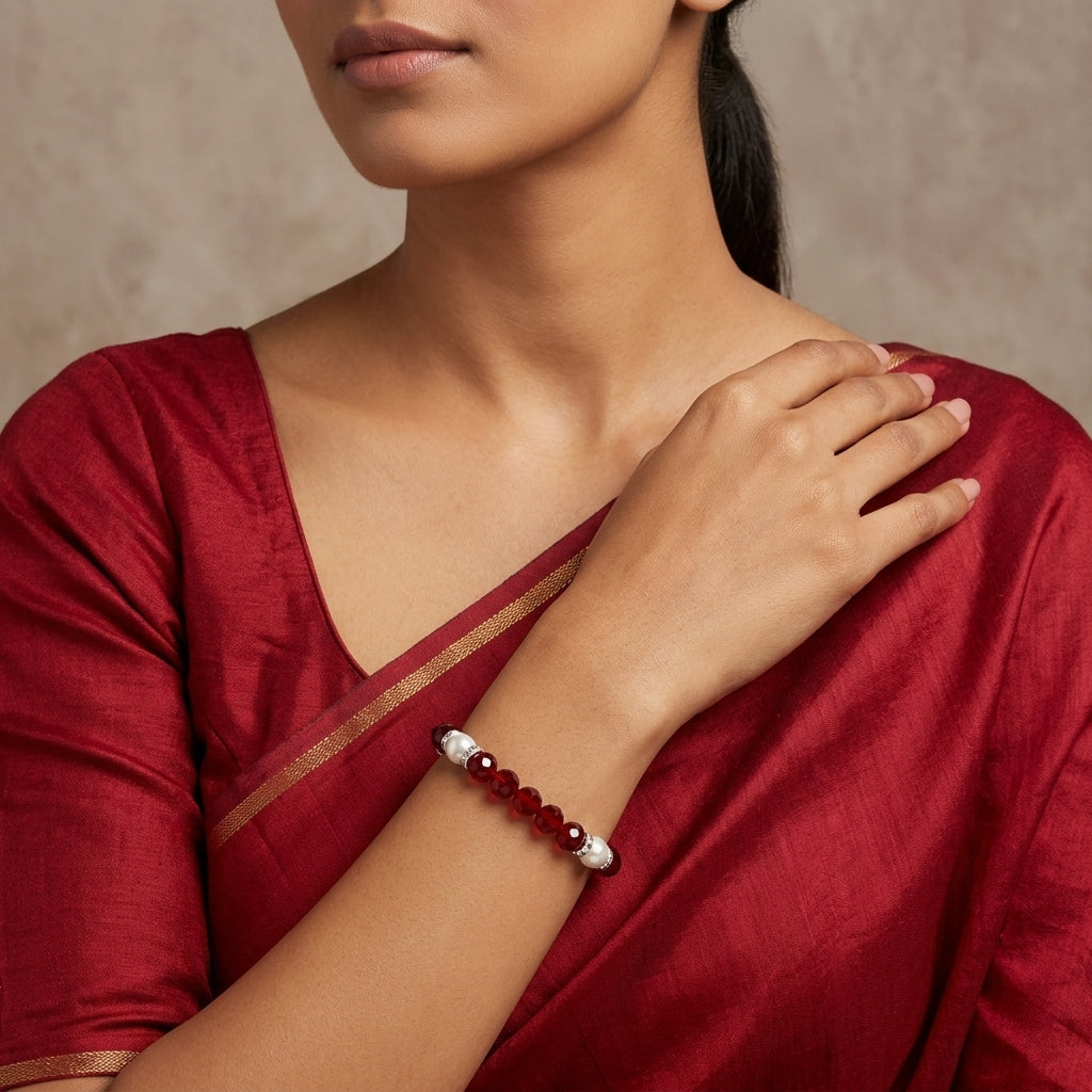Woman wearing a red dress with a close-up of her arm and a red beaded bracelet.