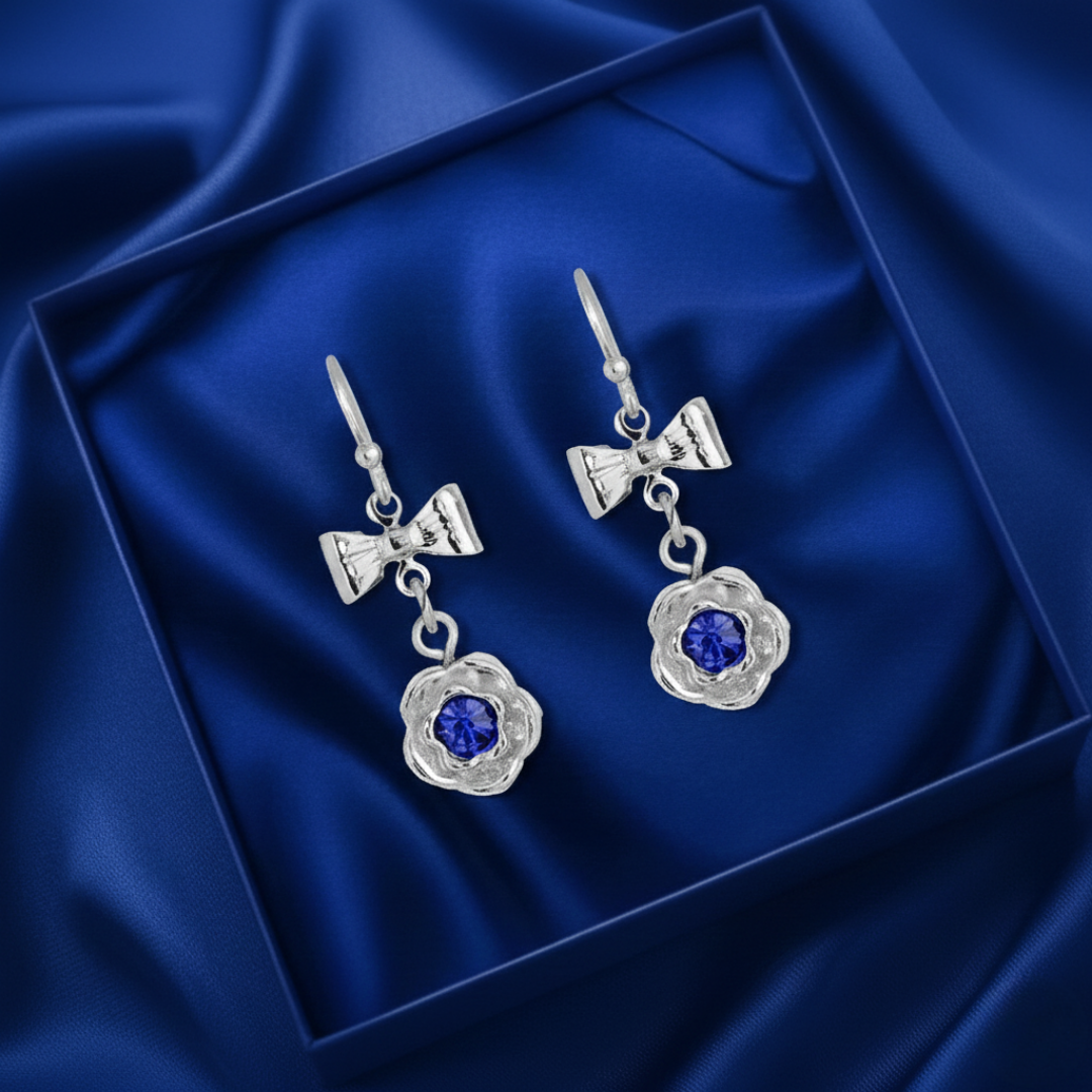 Silver earrings with blue gemstones on a blue satin background