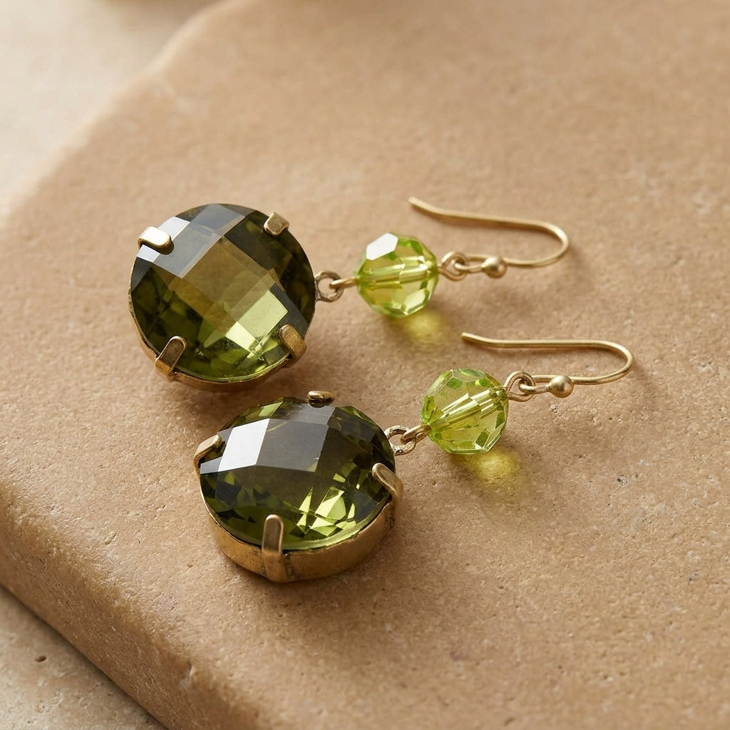 Round Green Stone Dangle Earrings resting on smooth tan-colored stone