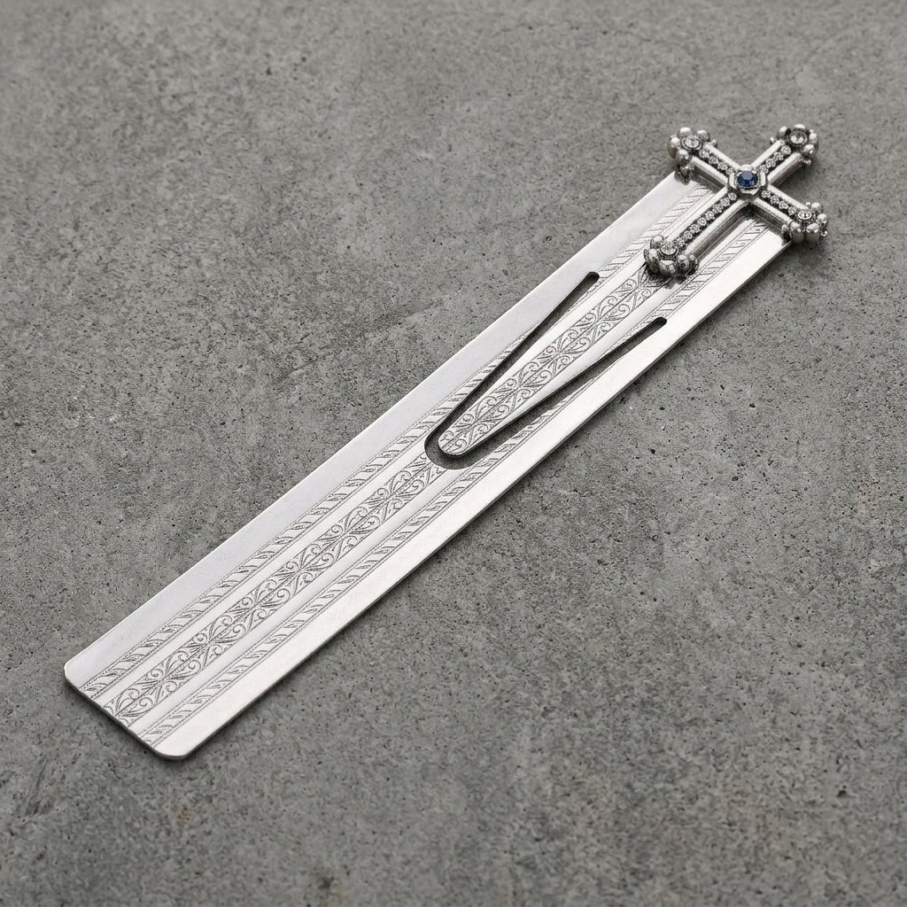 Silver bookmark with cross and floral design on a gray surface