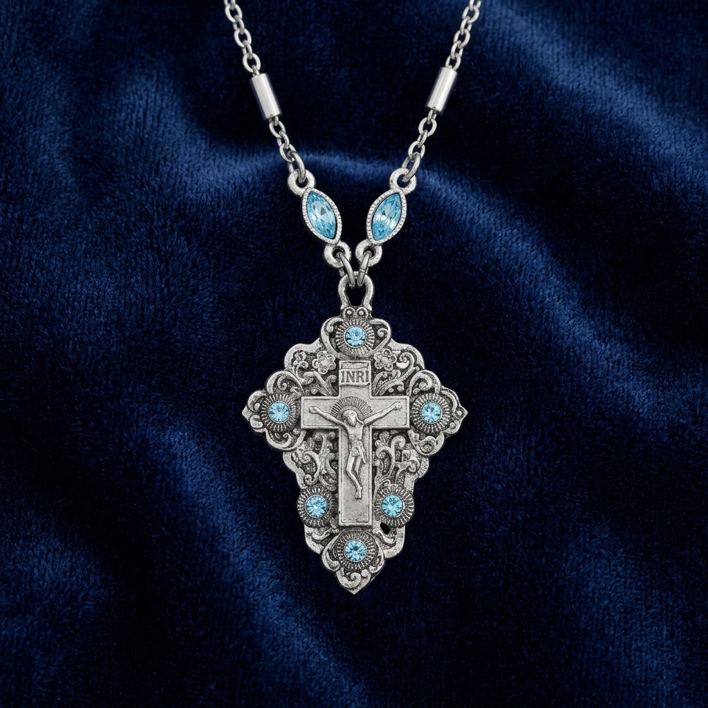 Silver necklace with a detailed cross crucifix pendant on a dark blue fabric background