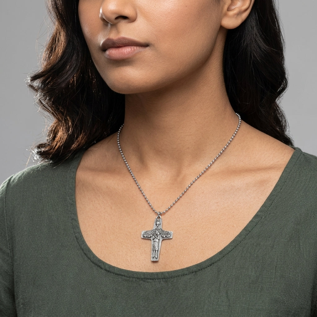 Woman wearing a silver necklace with a cross pendant on a gray background