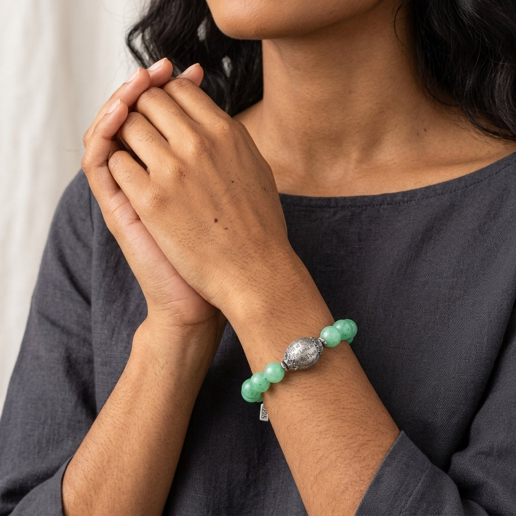 Person wearing a green beaded Hail Mary bracelet with a neutral background