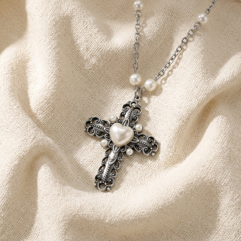 Silver cross necklace with faux pearl heart pendant and pearls on a beige fabric background