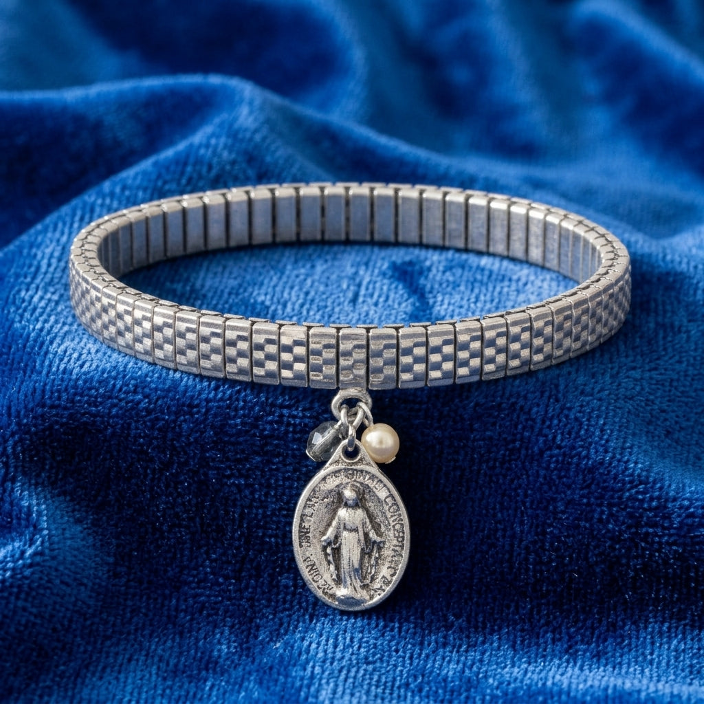 Silver bracelet with a Jesus charm and pearl on a blue fabric background