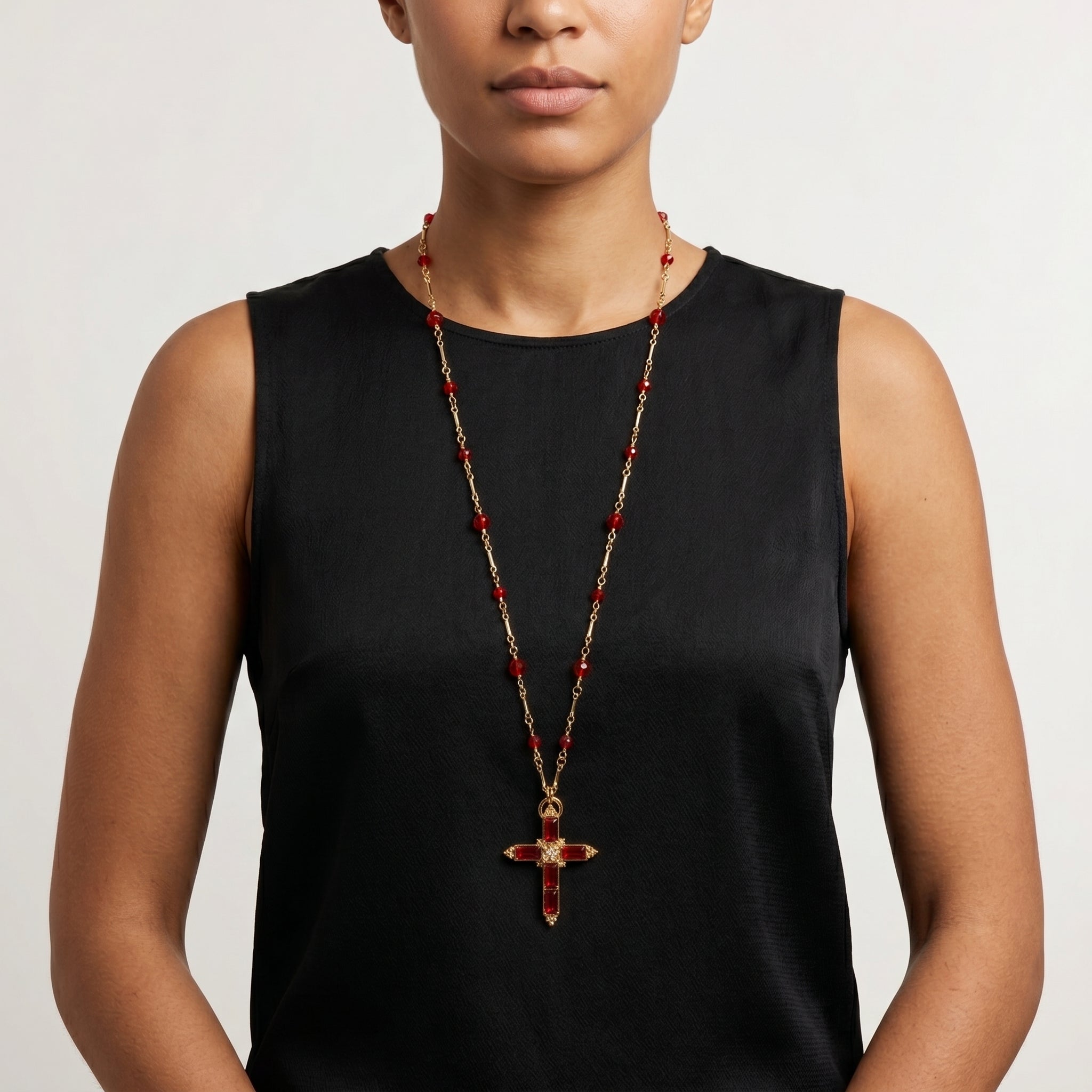 Woman wearing a siam Red crystal cross necklace with red beads on a gold tone chain