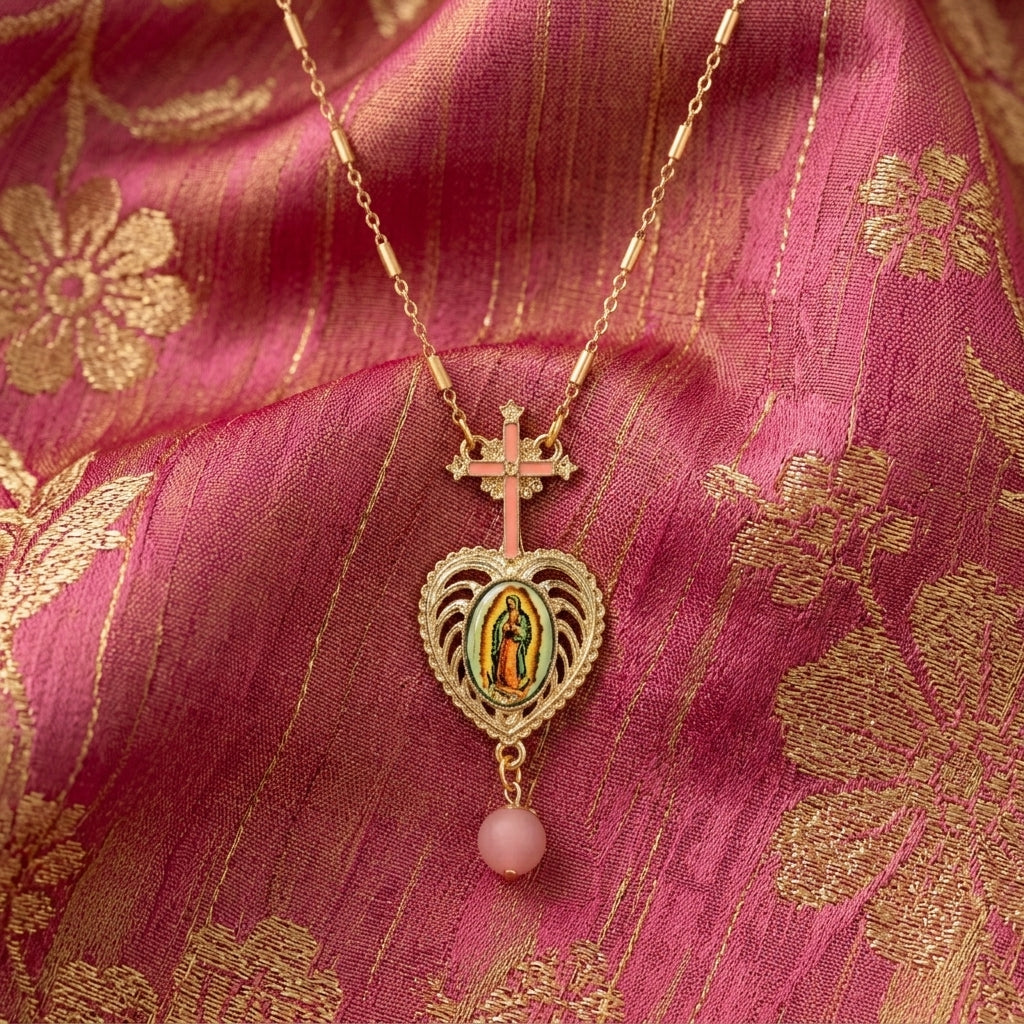 Gold necklace with a heart-shaped pendant featuring a religious figure on a pink fabric background