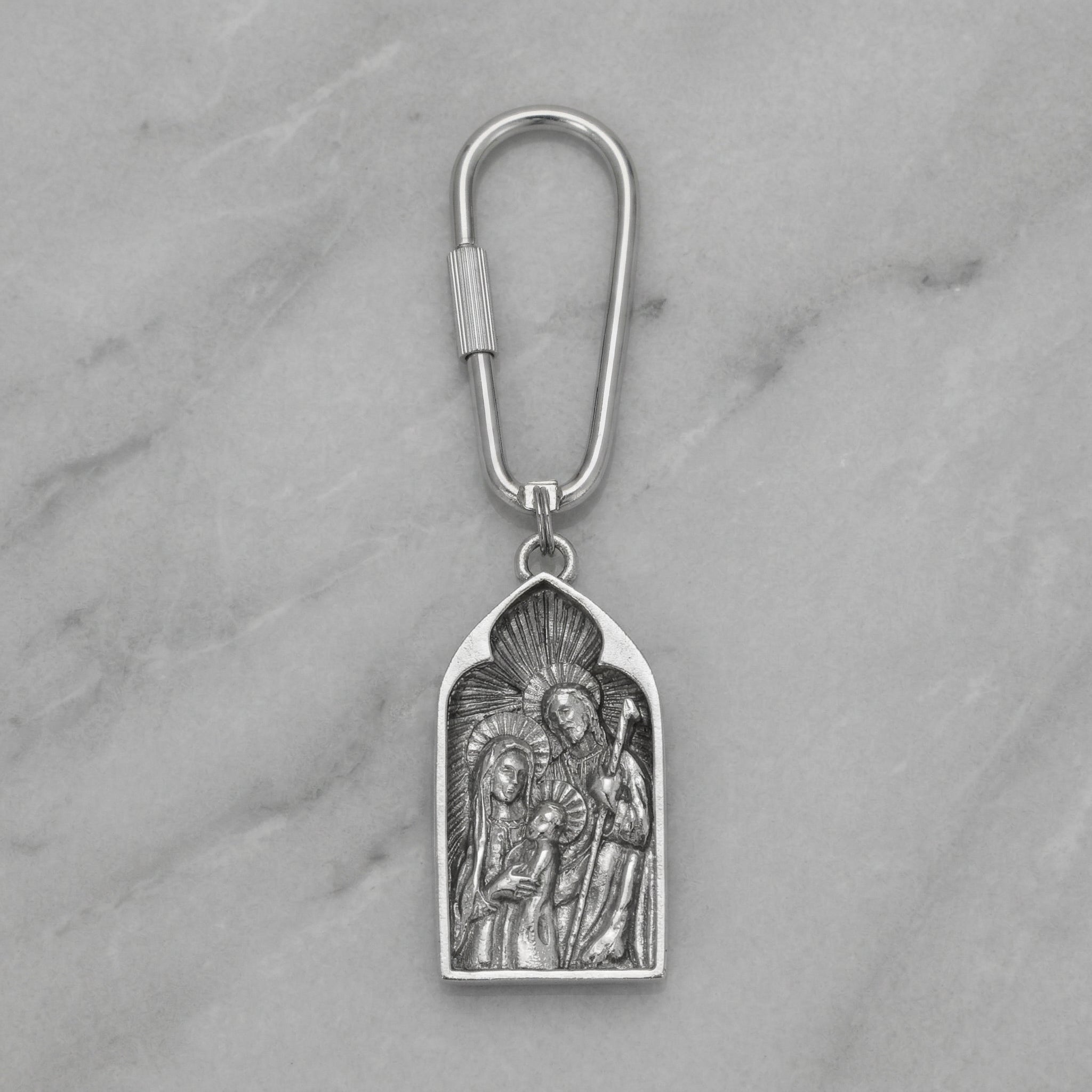 Silver keychain with religious design on a marble surface