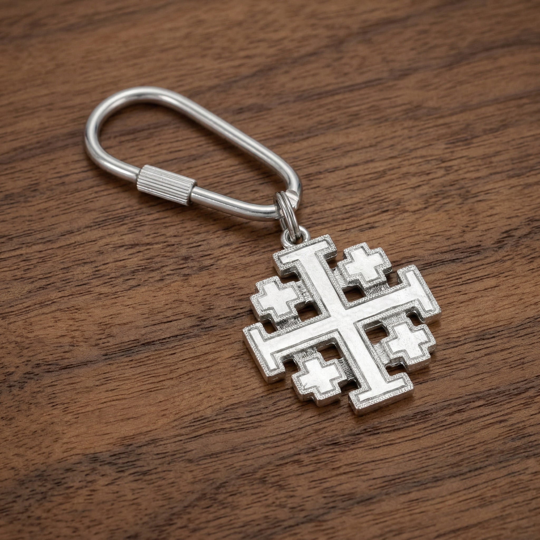 Silver Jerusalem cross keychain on a wooden surface