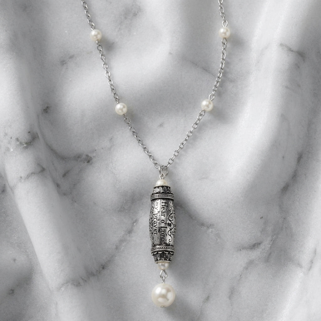 Religious necklace with bible snippets and white faux pearls and an ornate pendant on a marble surface