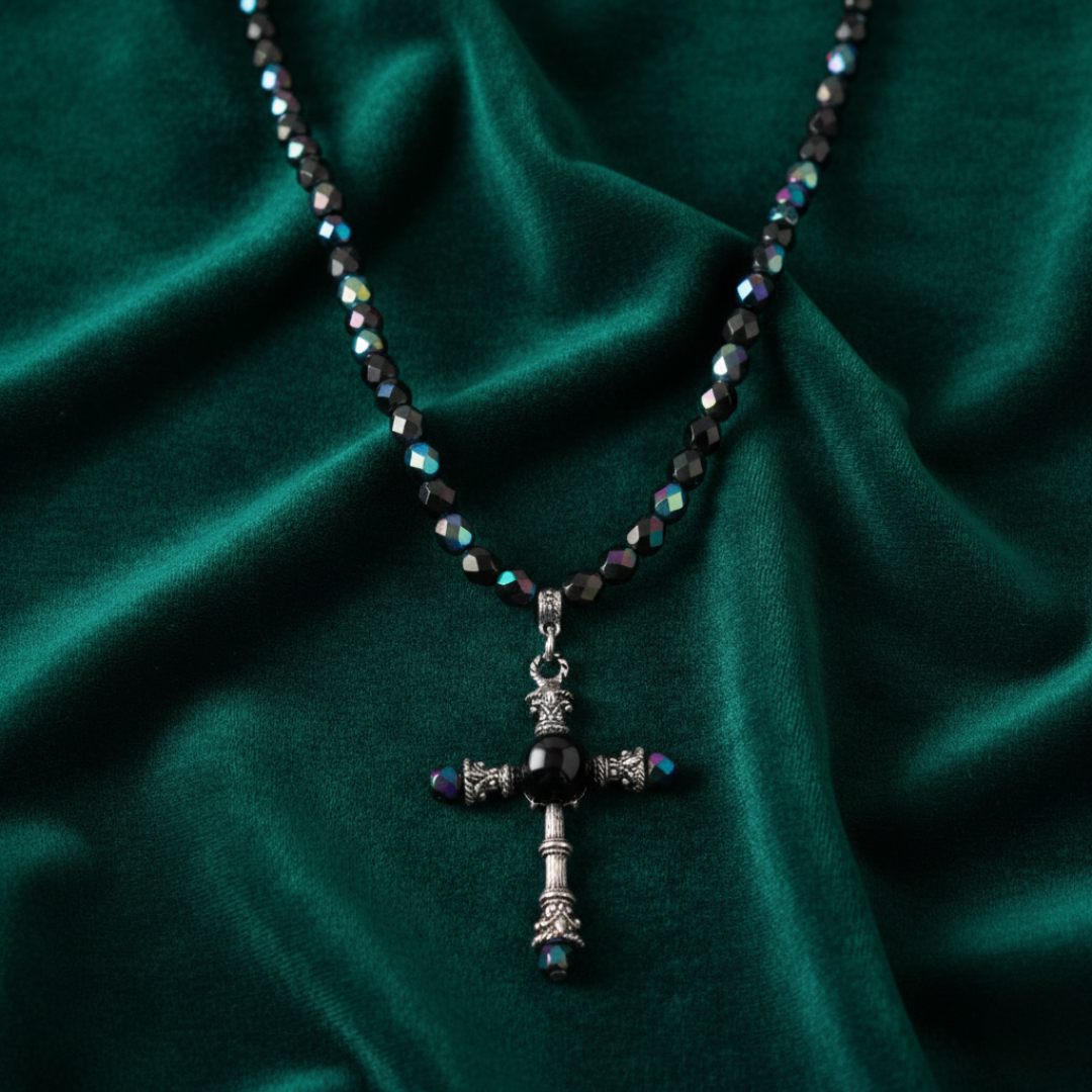 Necklace with a cross pendant on a green fabric background.