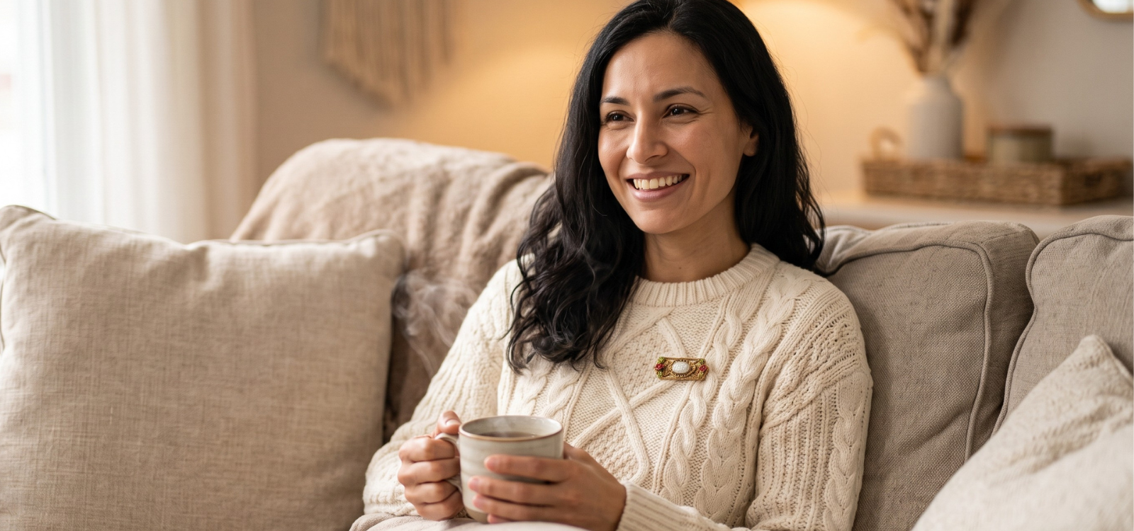 Woman in a comfy knitted sweater sitting on the couch with a cup of coffee and a pearl and gold tone brooch pin.