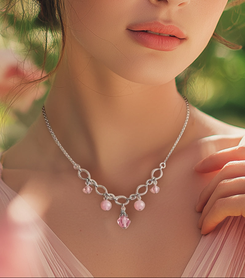 Woman wearing a silver necklace with pink beads against a blurred natural background