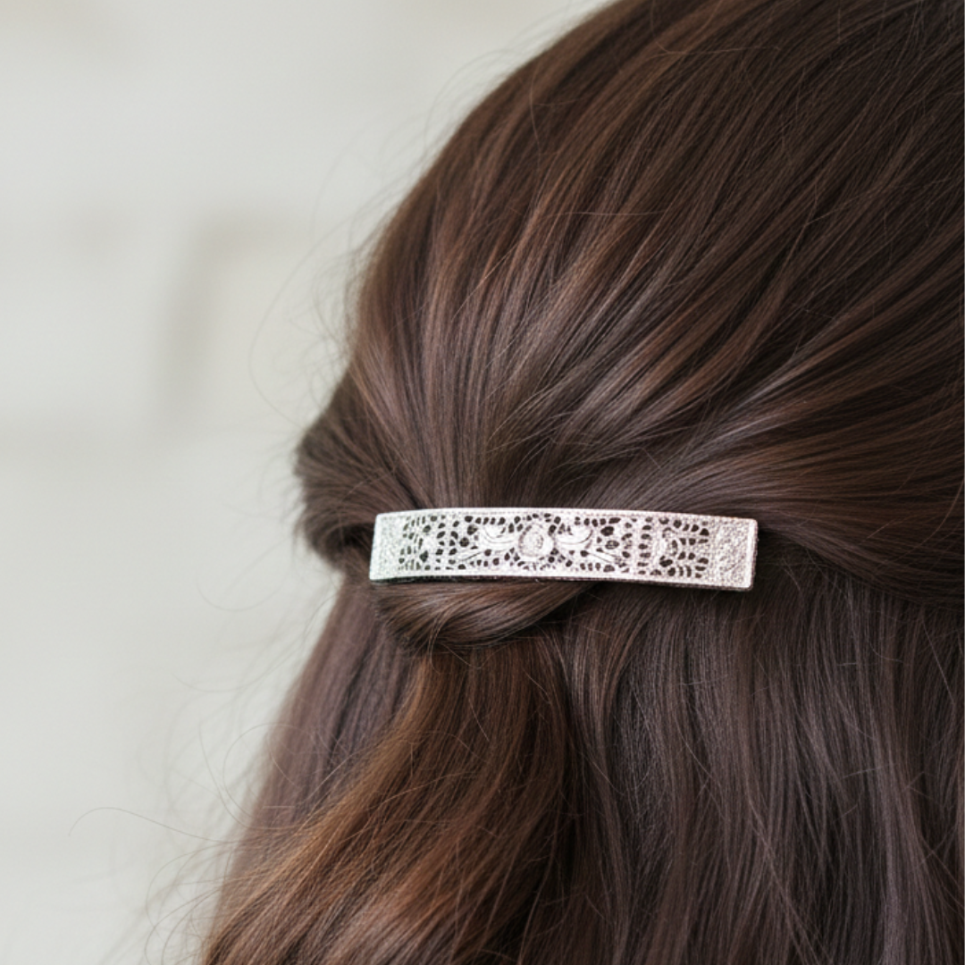 Silver tone floral barrette clipped into the hair of a woman.