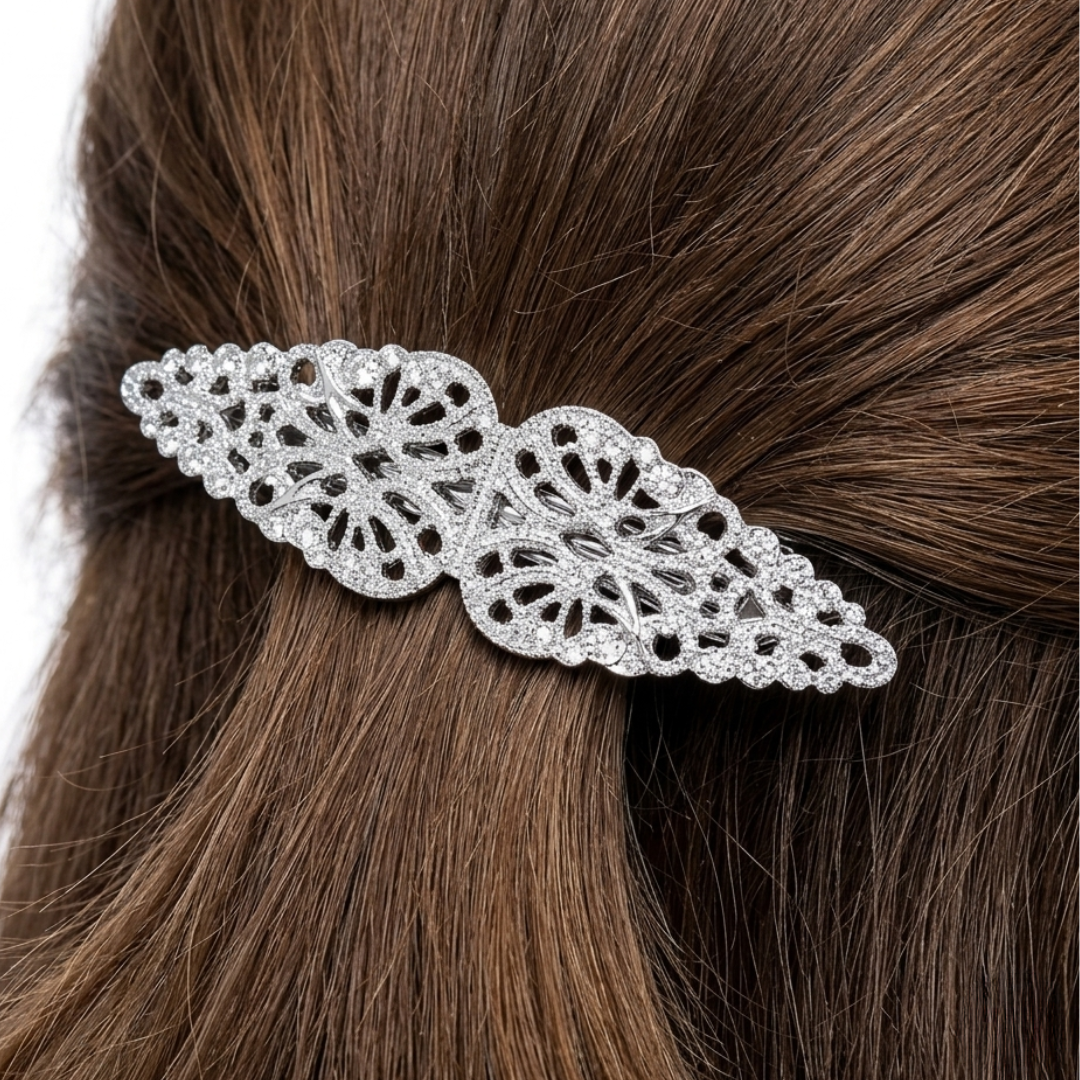 Decorative silver hair barrette on brown hair against a white background