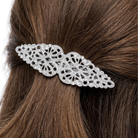 Decorative silver hair barrette on brown hair against a white background