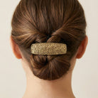 Person with a bun wearing an ornate Gold Floral Hair Barrette