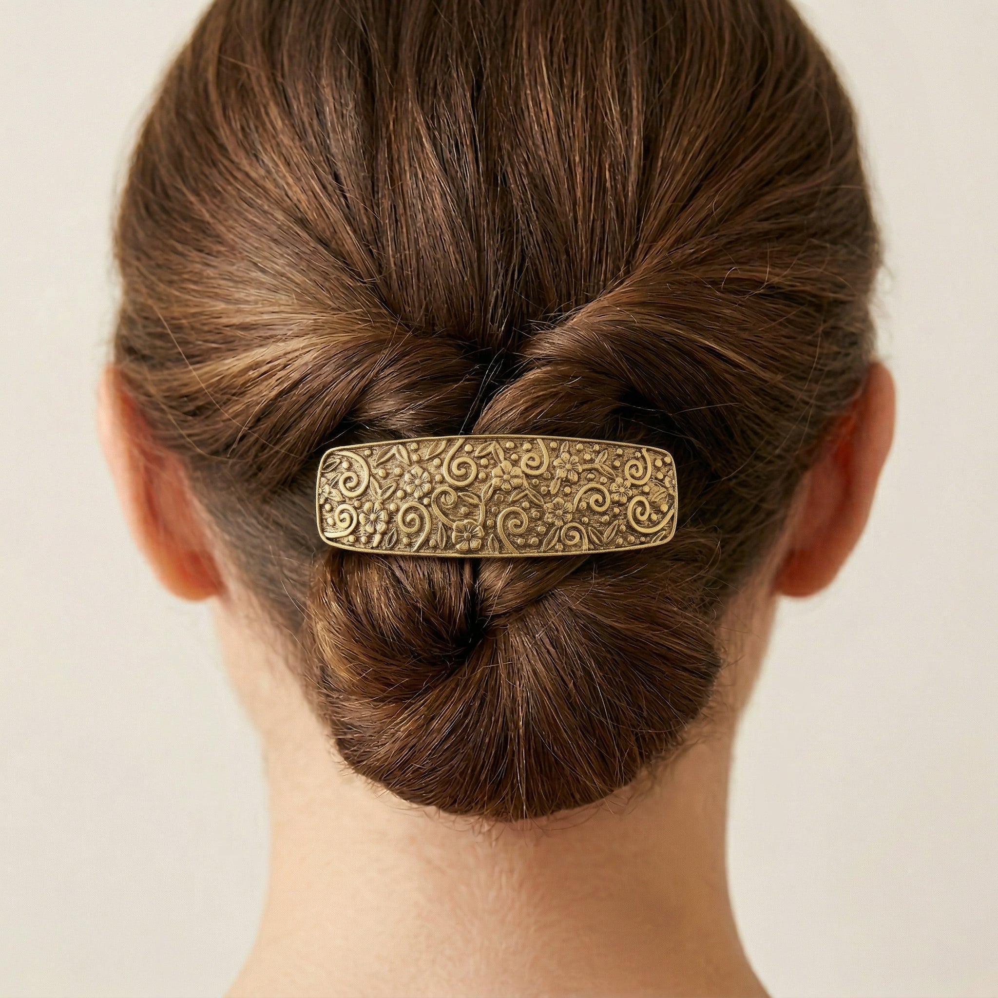Person with a bun wearing an ornate Gold Floral Hair Barrette
