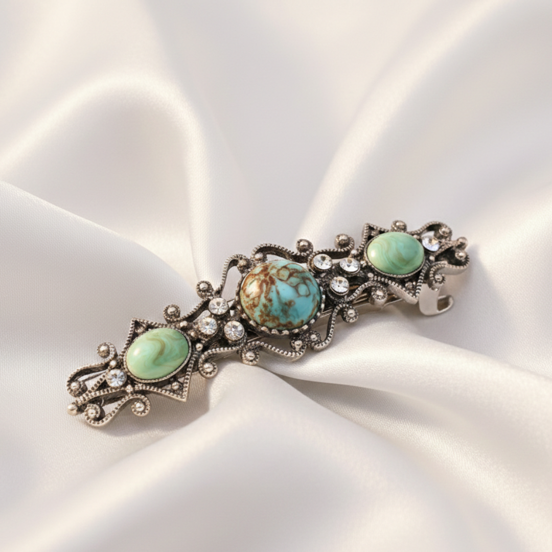 Decorative hair barrette with turquoise stones on a white satin background