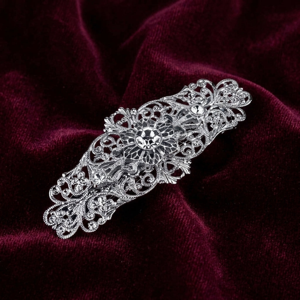 Silver decorative brooch on a burgundy velvet background