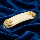 Oval Ivory Fleur de Lis Hair Barrette on a blue fabric background