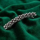 Silver hair clip with crystals on a green fabric background