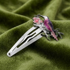 Multicolor Perched Bird & Flower Snap Hair Clip on a green fabric background