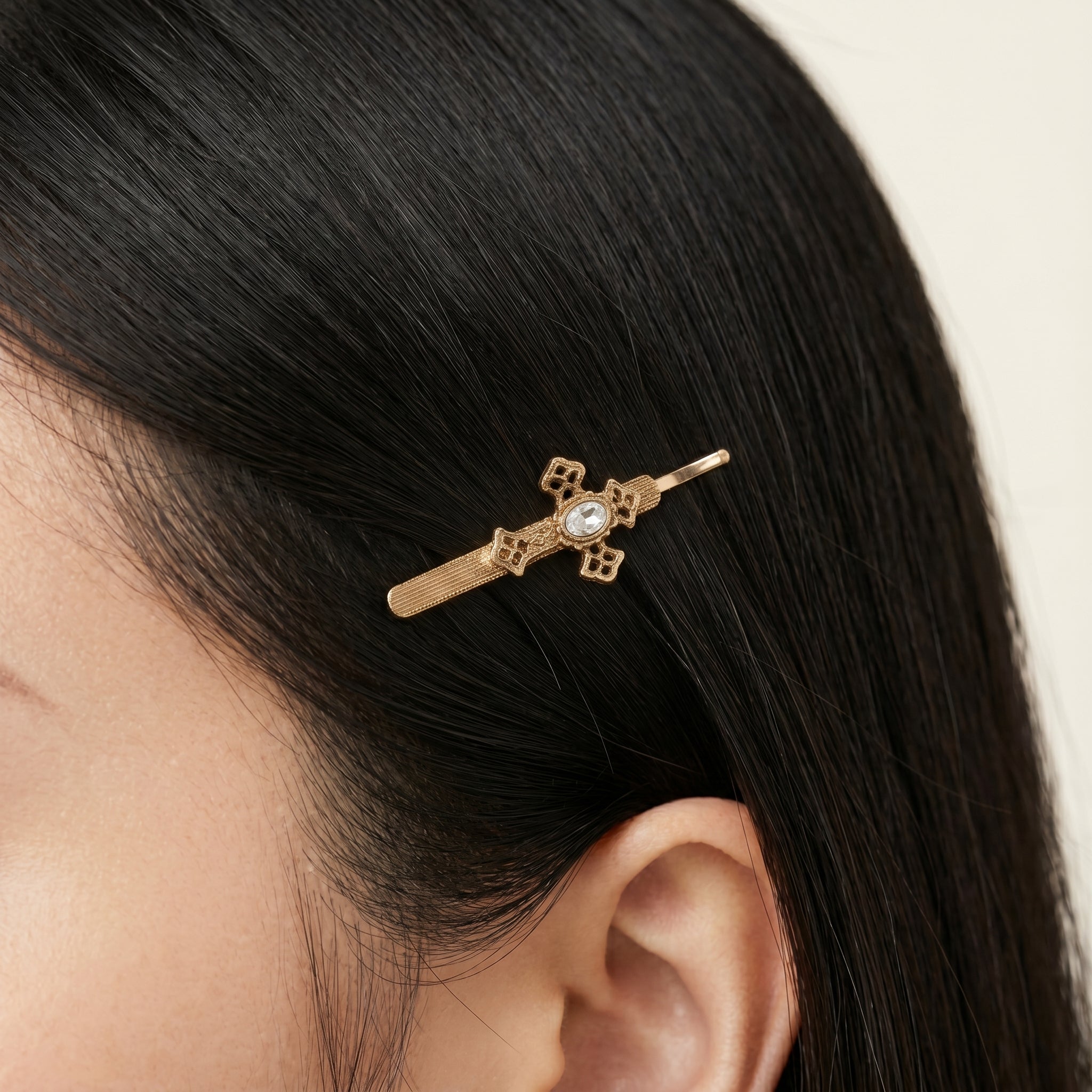 Gold tone Oval Glass Crystal Cross Bobby Pin in a woman's dark hair