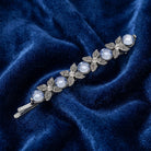 Blue crystal and silver tone floral bobby pin hair clip laying on dark blue velvet fabric 