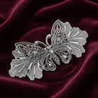 Silver butterfly barrette on a dark red satin background
