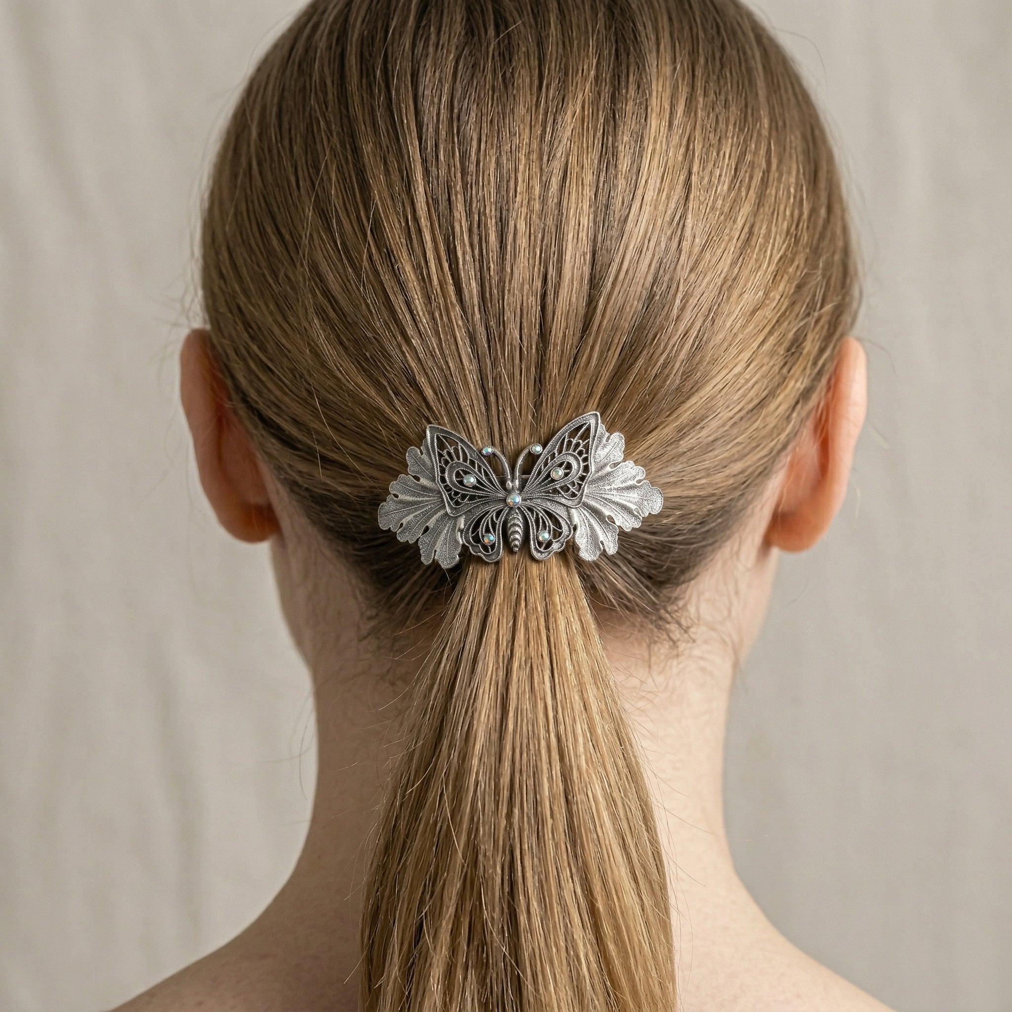 Butterfly hair clip in a person's hair against a neutral background