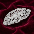 Silver floral barrette on burgundy-colored fabric 