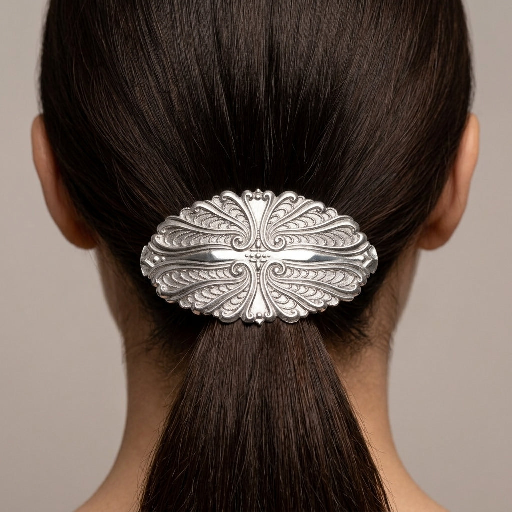 Decorative silver barrette on a person's hair against a neutral background