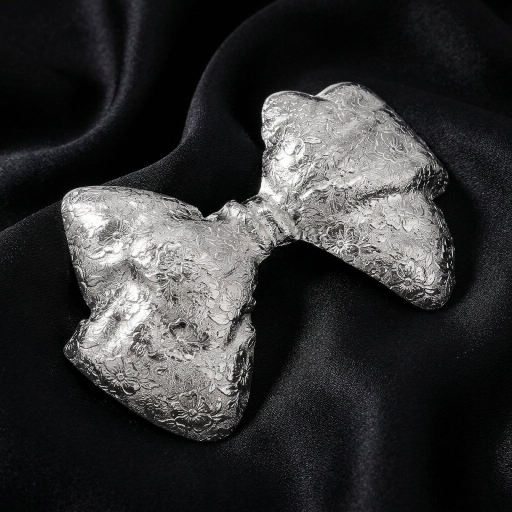 Silver-colored hair barrette on a black fabric background