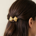Woman with dark hair wearing a gold tone Floral Bow Silver Hair Barrette