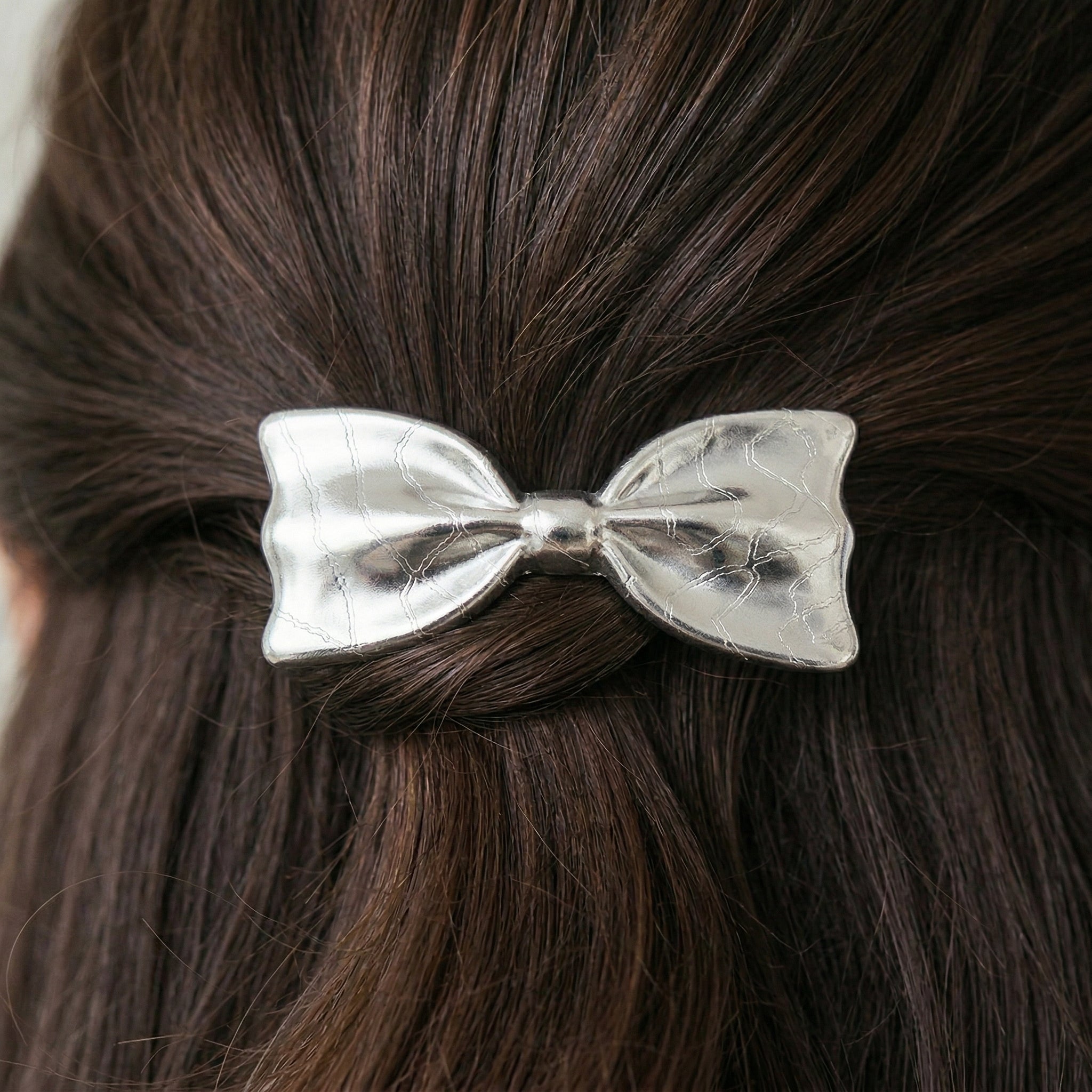 Silver bow hair clip barrette on brown hair
